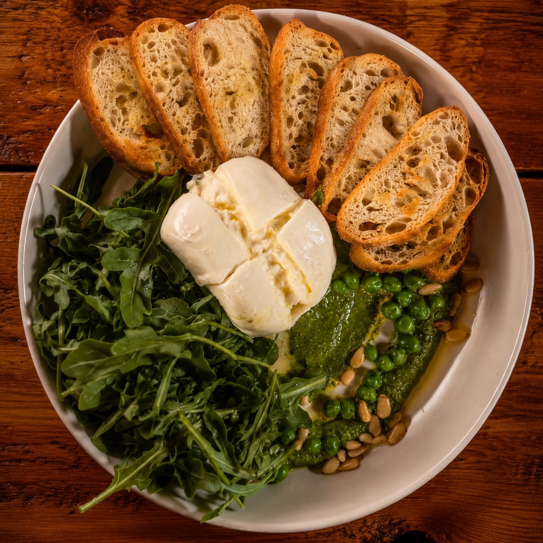 Burrata with spinach pesto, spring peas, pine nuts and crostini