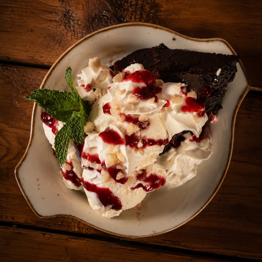 Café brownie with raspberry coulis, vanilla ice cream and whipped cream